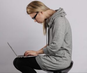 Activities of Daily Life and Posture: What Personal Trainers Need to Know 5 Bad Posture Effects.Female Student Using Laptop And Suffering From Back Pain