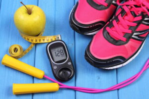 Training the Diabetic Client 2 Glucometer, Sport Shoes, Fresh Apple And Accessories For Fitness On Blue Boards