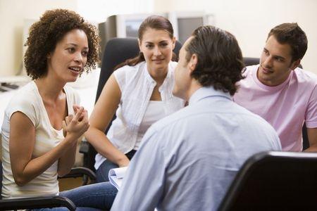 man giving lecture to three people in room