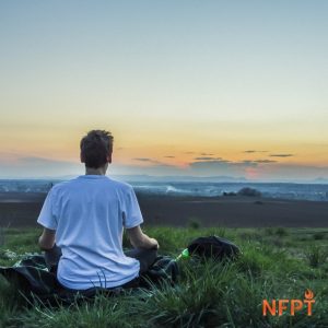 man meditating by sunset