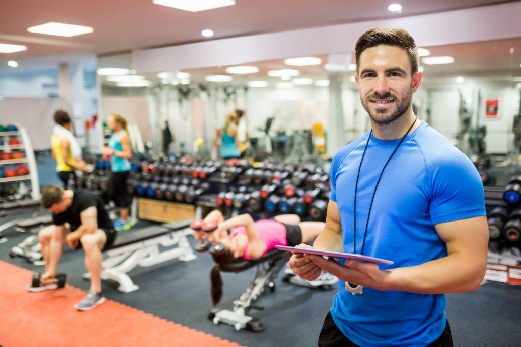 47306226 - handsome trainer using tablet in weights room at the gym