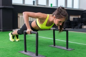 Young Fit Woman Doing Horizontal Push Ups With Bars In Gym.